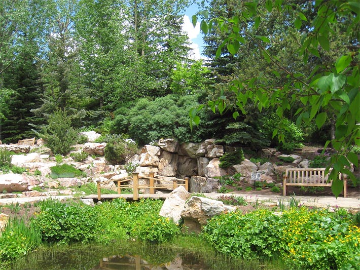 Alpengarten Betty Ford mit bepflanzter Steinmauer und Miniatur-Bergsee mit Holz-Bank