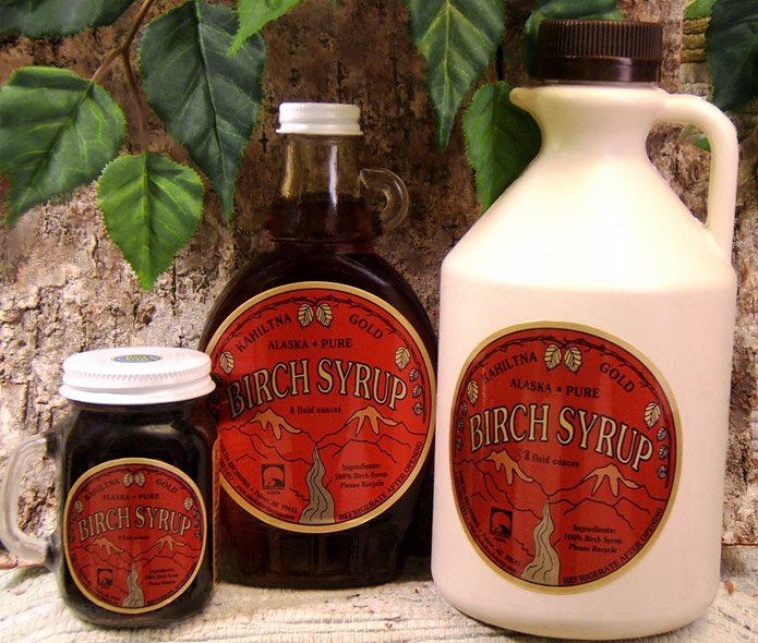 Verschieden große Flaschen von Birkensirup mit rotem Etikett und Beschriftung `Kahiltna Gold Alaska Pure Birch Syrup`