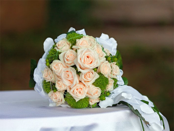 Brautstrauß mit blaß-orangen Rosen und dekoriert mit grünen Moosen