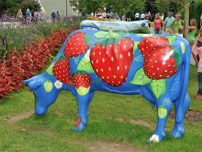 Gartenkuh lebensgross mit einem Erdbeer-Muster in einer öffentlichen Gartenanlage
