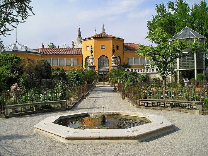 Brunnen im Zentrum des Botanischen Gartens Padua, italienisch Orto Botanico, und dem Gewächshaus rechts dahinter im Bild, in dem sich die Goethe-Palme befindet