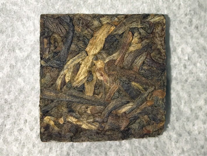 Quadratische, dunkelbraune Stücke von getrocknetem, gepresstem Pu-Erh-Tee der Sorte Shou