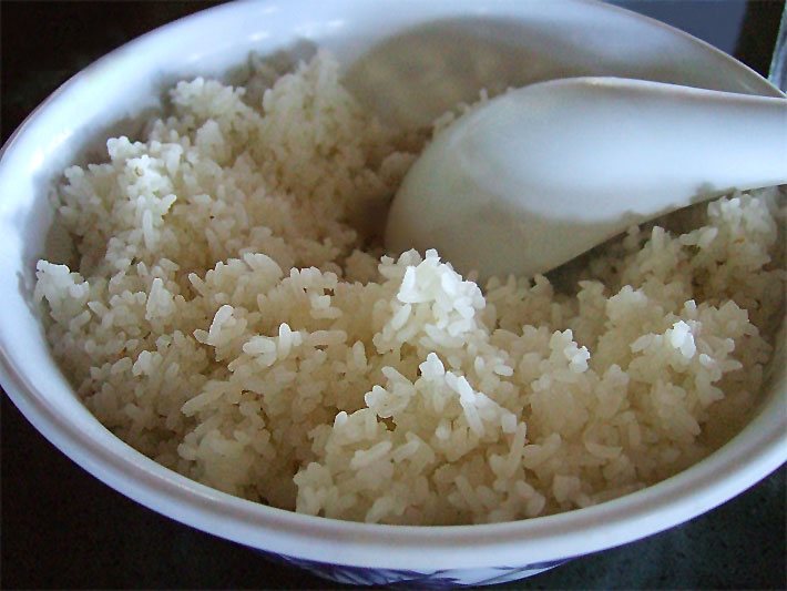 Asiatische Porzellan-Schale mit gekochtem Reis und Esslöffel