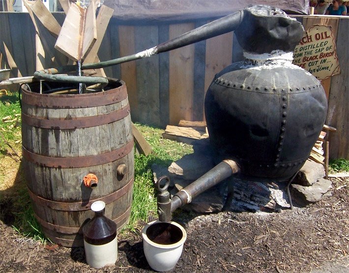 Einfacher Aufbau einer Birkenbier-Destillation mit einem Kessel braun-schwarzem Destillat