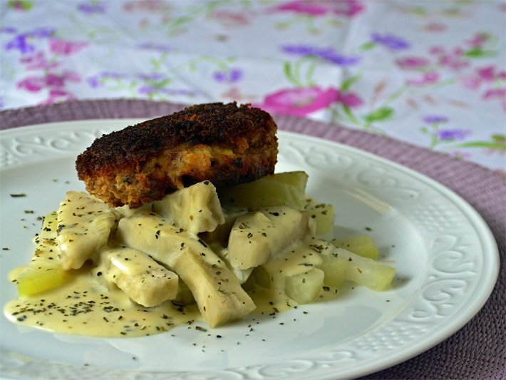 Kochrezept für Gemüse bestehend aus gekochten Yacon- und Kohlrabi-Stücken, Soße Hollandaise mit Kräutern und Cordon Bleu auf einem weißen Teller