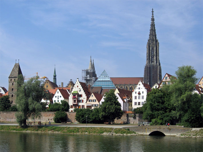 Die Altstadt von Ulm vom Donauschwabenufer aus mit dem Münster, dem Metzgerturm als Teil der Stadtbefestigung und den Spitzen von der neuen, gläsernen Stadtbibliothek und dem Rathaus.