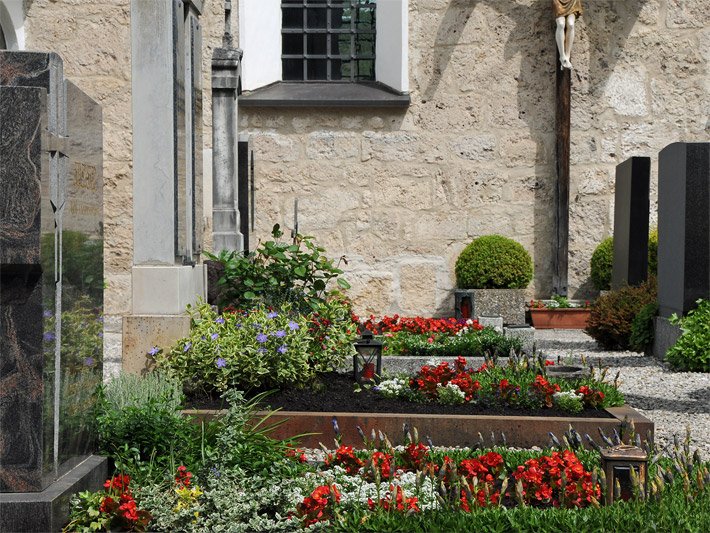 Friedhof mit Grabsteinen und bepflanzten Grabstätten im Oktober