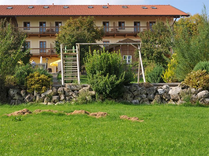 Garten mit Felssteinen als Trockenmauer am Hang als Abgrenzung von einem höher liegenden Spielplatz