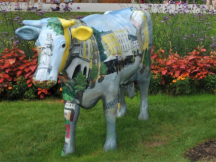 Lebensgrosse Kuh-Gartenfigur mit Altstadt-Malerei in einem öffentlichen Park