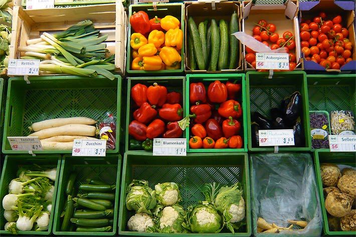 Bio-Gemüsestand in einem Supermarkt mit grünen Gemüsekisten gefüllt mit Lauch/Porree, Paprika, Salat-Gurken, Tomaten, Rettich, Auberginen Keimsprossen, Fenchel, Zucchini, Blumenkohl, Pastinaken und Sellerie