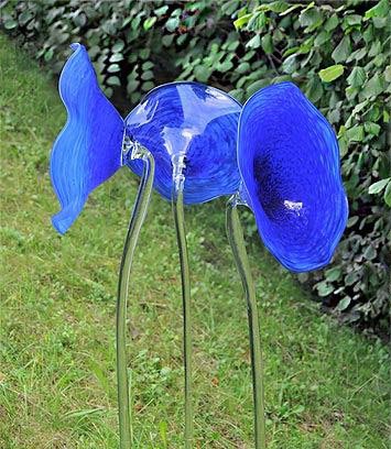 Trichterförmige, blaue Glasblumen als Glaskunst auf einer Gartenwiese