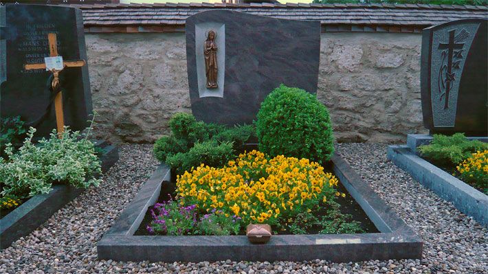 Grabblumen und Beispiele für die Grabbepflanzung auf einem Friedhof mit Kriech-Wacholder und Buchsbaum