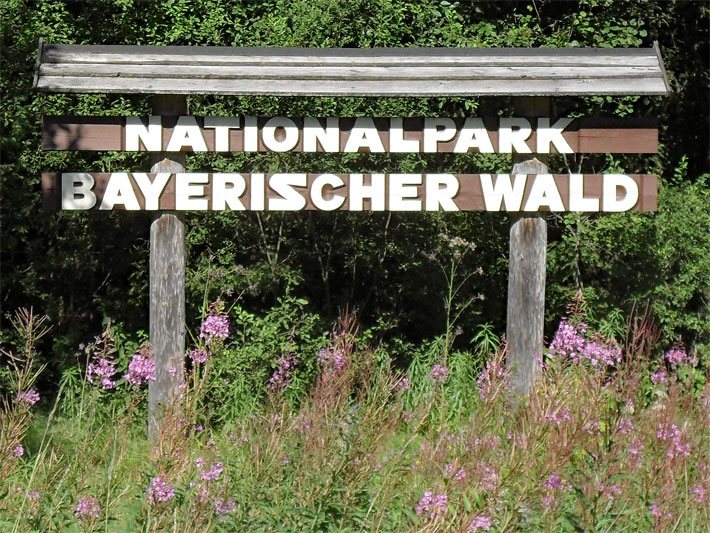 Grenzschild aus braunem Holz mit weissem Schriftzug vom Nationalpark Bayerischer Wald