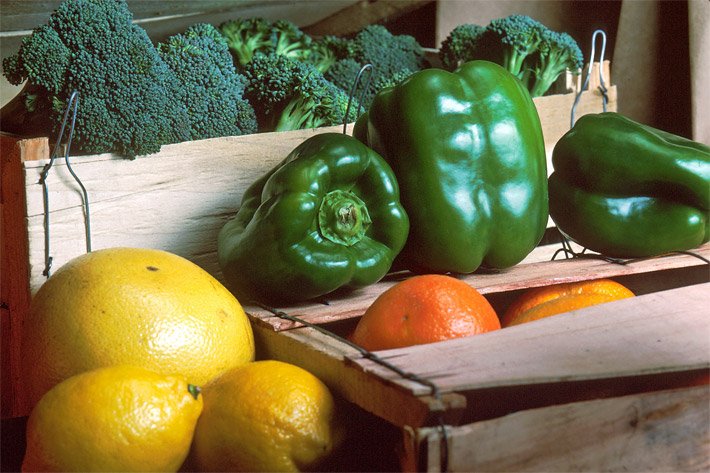 Obst-, Gemüsekisten-Abo mit drei orangen Mandarinen, daneben liegend eine gelbe Grapefruit und zwei gelbe Zitronen, dahinter drei grüne Paprika und sechs grüne Brokkoli-Röschen