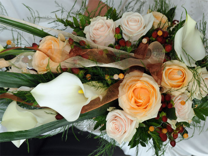 Strauss mit Blumen zur Hochzeit mit blass-rosa und orangen, gefüllten Rosen sowie Callas, botanischer Name Zantedeschia, mit weißem  Hochblatt (Spatha), das einen hell-gelben Kolben umgibt  