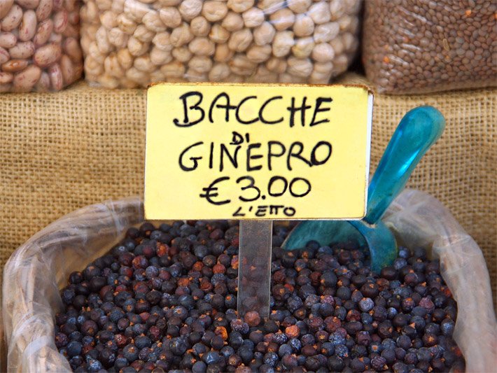 Ein Korb mit Wacholderbeeren und einem gelben Preisschild mit der italienischen Beschriftung Bacche Di Ginepro € 3,00 L`etto