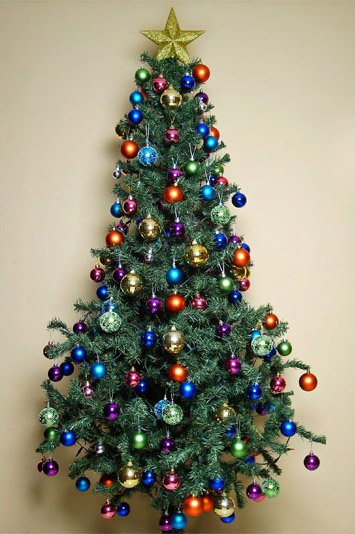 Kleiner Weihnachtsbaum geschmückt mit verschieden farbigen Christbaumkugeln und einem auf die Baumspitze aufgesetzten, goldenen Weihnachtsstern mit fünf Zacken