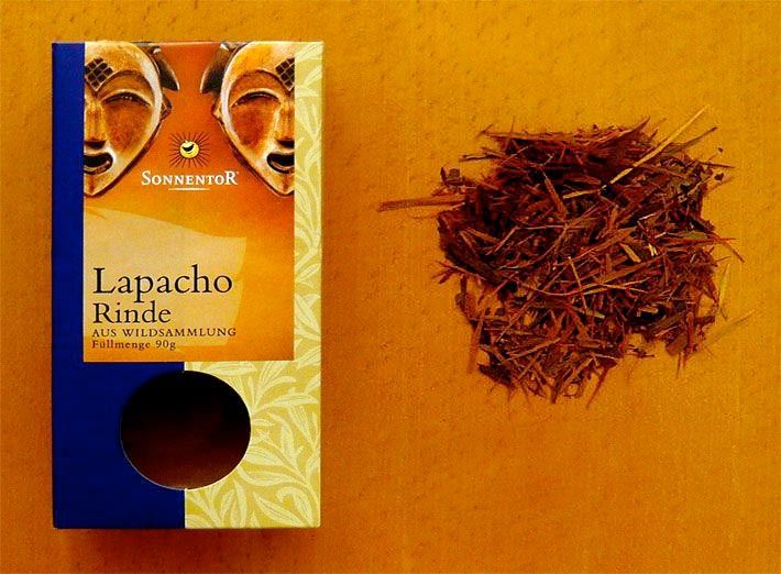 Bio-Lapacho-Rinde aus Wildsammlung der Firma Sonnentor auf einer rötlich-braunen Holztischplatte