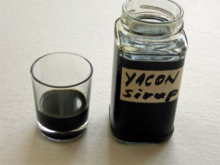 Bio Yacon-Sirup nach dem selber Machen mit braun-schwarzer Farbe in einem Glas und einer Flasche